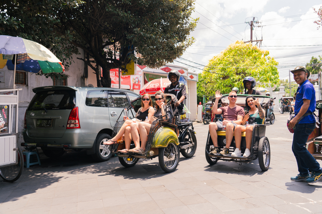 Reizigers maken een rit met becak-fietstaxi’s op straat in Indonesië, tijdens de 22-35ers reis Java en Bali.
