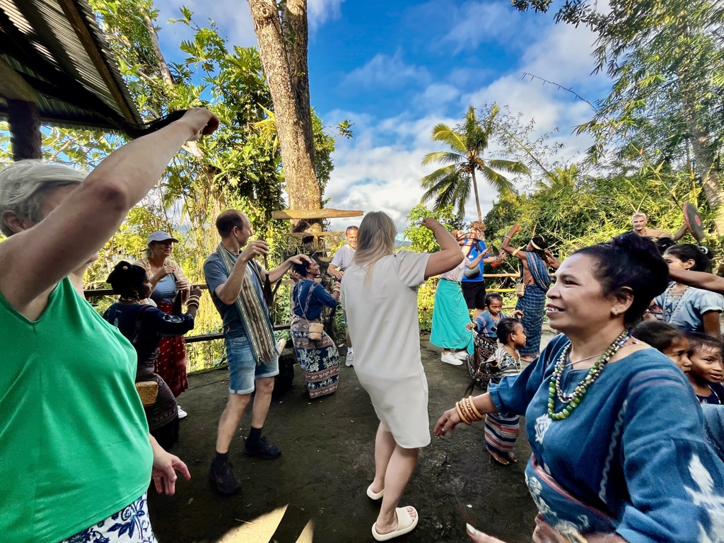 Familie danst met lokale bewoners tijdens een traditioneel dorpsfeest op de Kleine Sunda Eilanden, Indonesië.