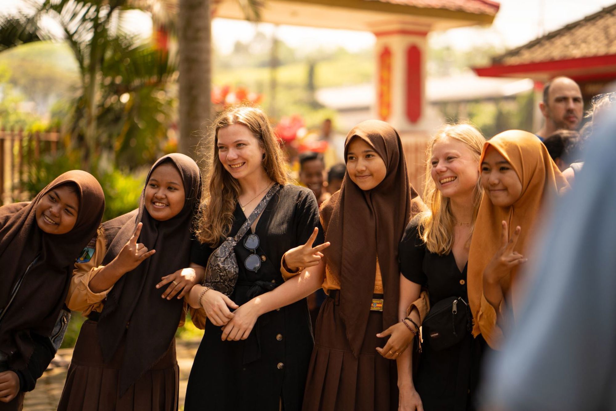 Toeristen poseren met lokale scholieren bij een bezienswaardigheid in Indonesië.