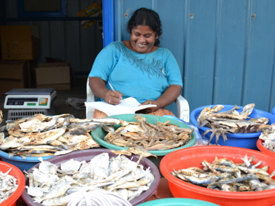 Vrouw noteert bestellingen bij een kraam met gedroogde vis op een markt in Sri Lanka.