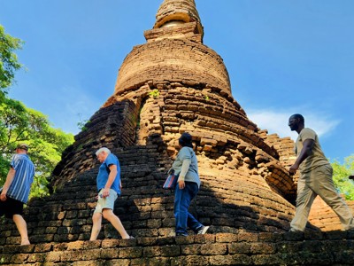 Reizigers bij een oude bakstenen stupa in Sukhothai Historical Park, Thailand.