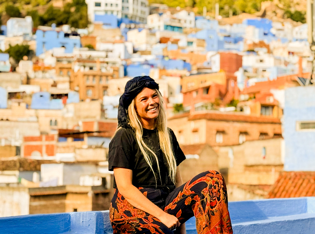 Reiziger met hoofddoek in Chefchaouen, met uitzicht op de blauwe huizen van Marokko.