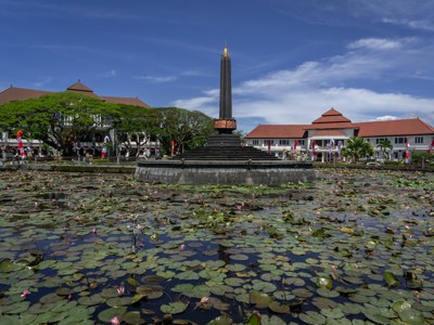 Monument Tugu Pahlawan in Surabaya, omringd door een vijver met waterlelies en koloniale gebouwen.