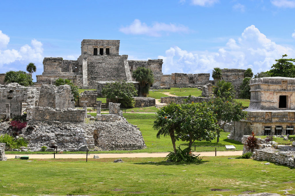Oude Mayaruïnes en piramide in Tulum, Mexico, met palmbomen en blauwe lucht.