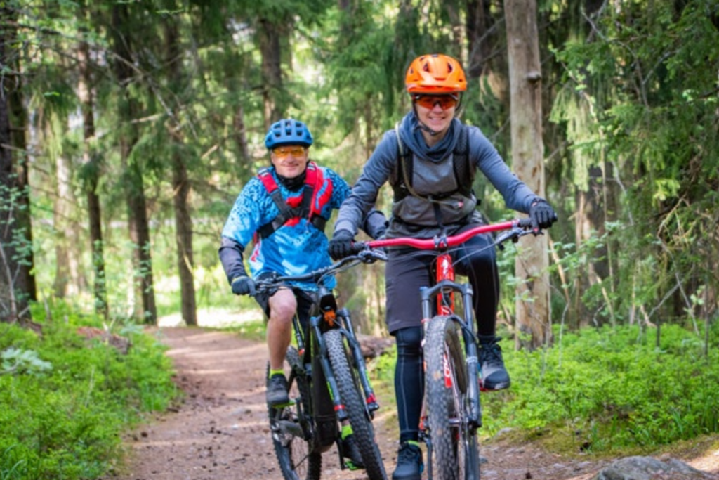 Twee mountainbikers fietsen door een bos in Scandinavië tijdens een groepsrondreis.