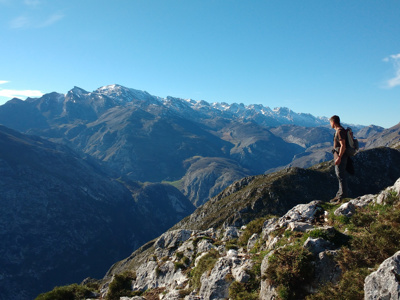 Wandelaar met rugzak kijkt uit over de bergtoppen van Picos de Europa in Spanje.
