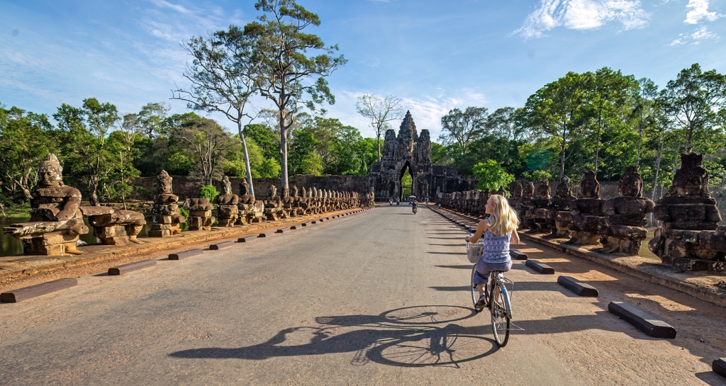 Fietser op de brug met beelden richting de Angkor Thom-poort in Cambodja.