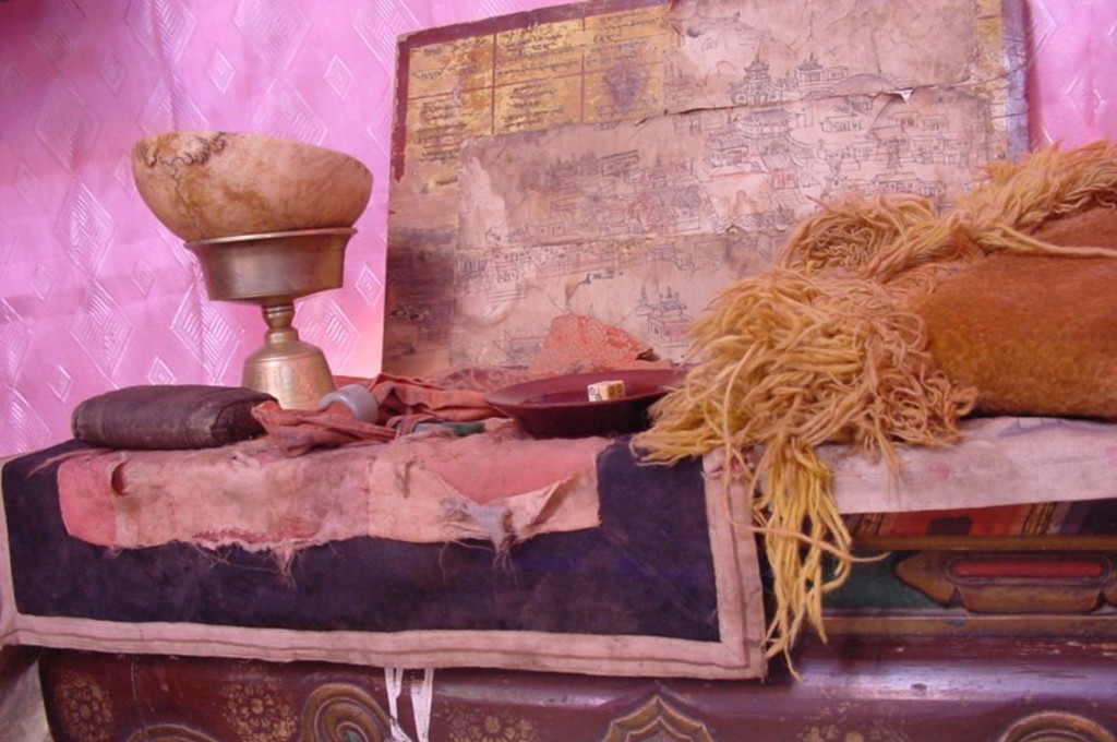 Interieur van een Mongoolse ger met kussens, een kom en een wandtekening tijdens een groepsrondreis Mongolië.