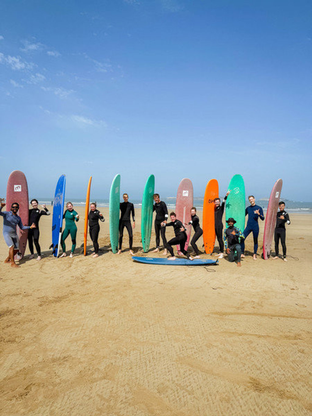 Groep 22-35ers met surfplanken op het strand tijdens rondreis door Marokko.