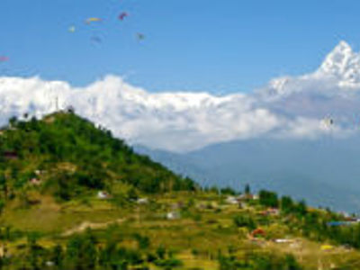 Uitzicht op groene heuvels met terrassen en besneeuwde Himalaya-bergen tijdens de Route Nepal.