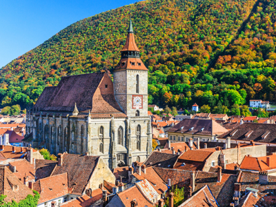 Zwarte Kerk in Brașov met rode daken en beboste heuvels op de achtergrond, route Roemenië.