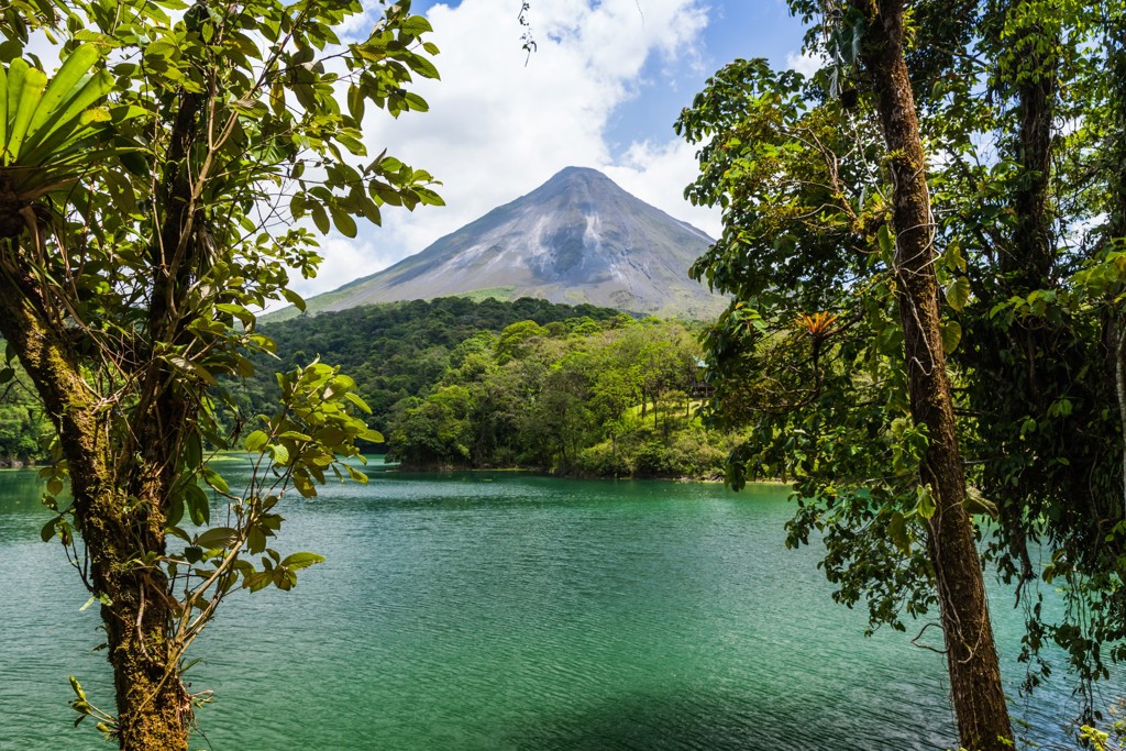 Uitzicht op de Arenal-vulkaan en het groene regenwoud bij een helder meer in Costa Rica.