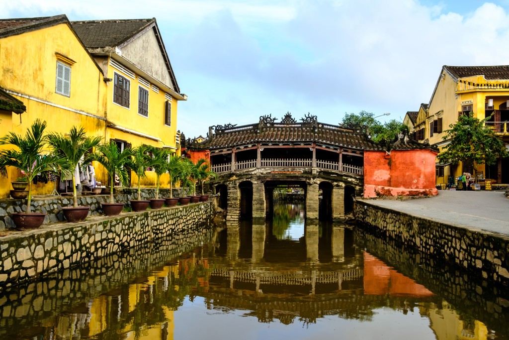 Japanse Brug in Hoi An met gele huizen langs het kanaal, Vietnam.