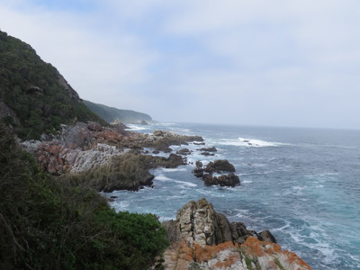 Rotsachtige kustlijn langs de Tuinroute in Zuid-Afrika, met golven die tegen de kliffen slaan.