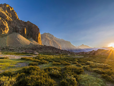Zonsopkomst boven een berglandschap in Bolivia en Chili, met groene valleien en rotsformaties.