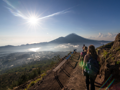 Wandelaars op bergpad met uitzicht op de Batur-vulkaan bij zonsopkomst op Bali.