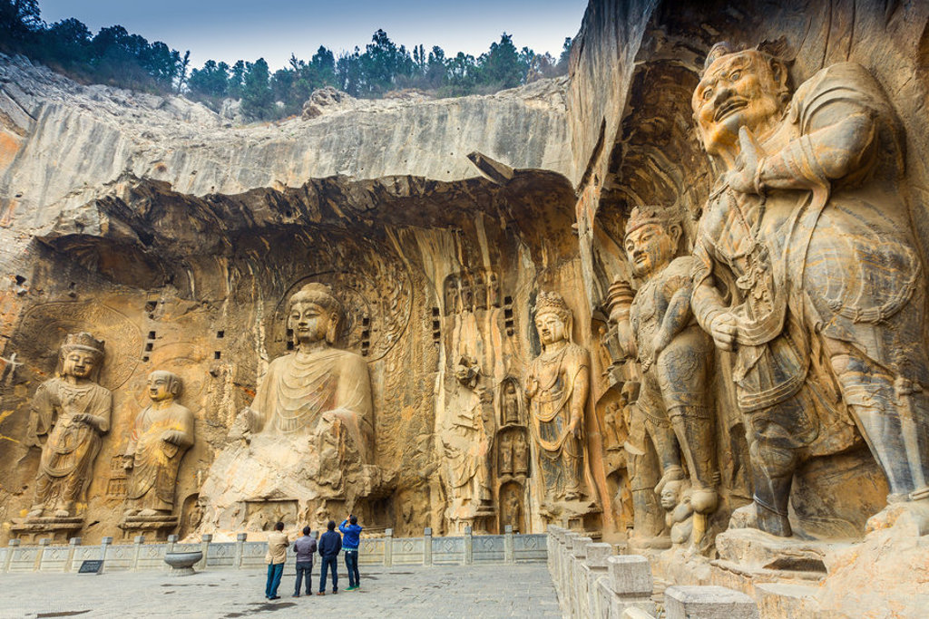 Groepsrondreis China hoogtepunten: bezoekers bij de uit rotsen gehouwen Boeddhabeelden van de Longmen-grotten.