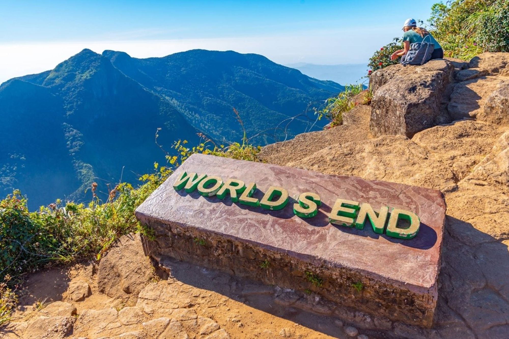 World’s End uitzichtpunt in Sri Lanka met bergpanorama en wandelaar op de rotsen.