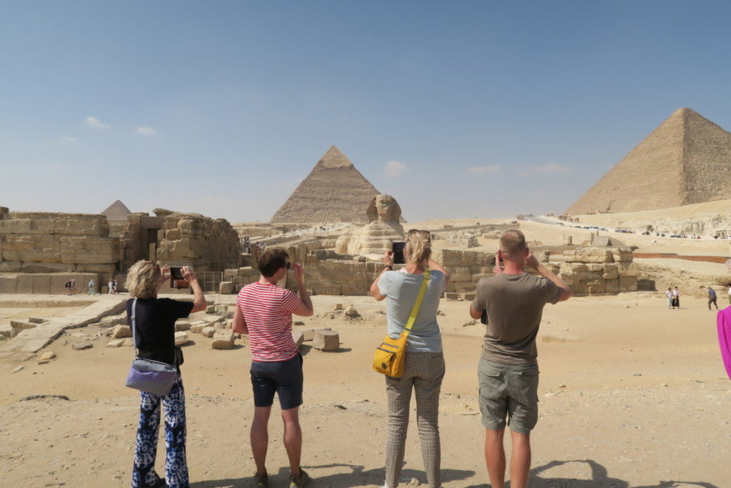 Reizigers fotograferen de Sfinx en de piramides van Gizeh tijdens een groepsrondreis Egypte.