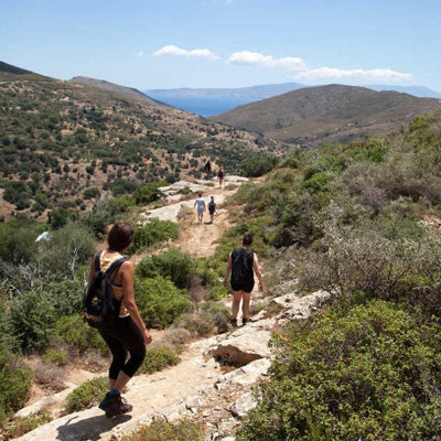 Wandelaars op een bergpad op Evia, Griekenland, met uitzicht op groene heuvels en de zee.