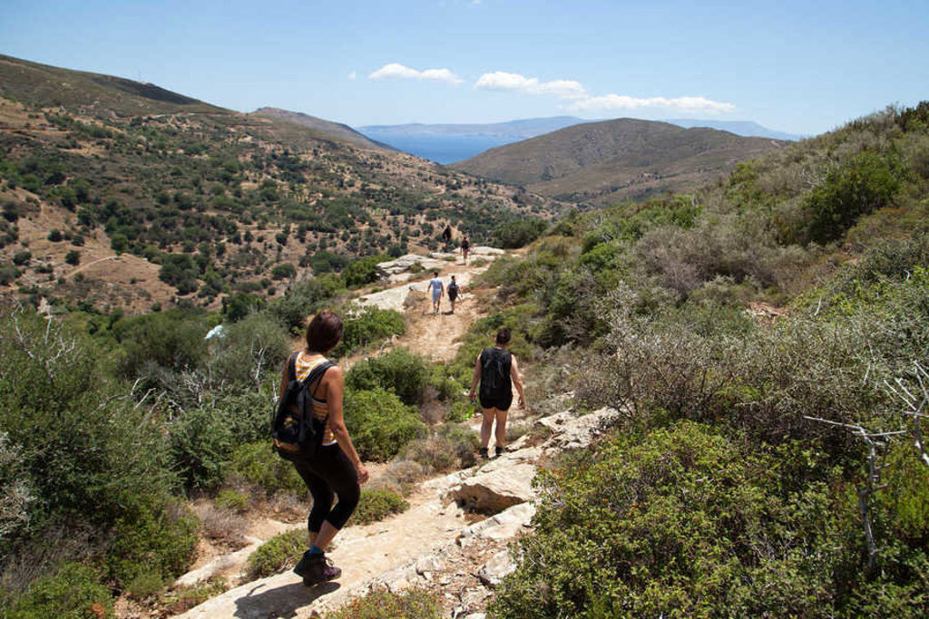 Wandelaars op een bergpad op Evia, Griekenland, met uitzicht op groene heuvels en de zee.