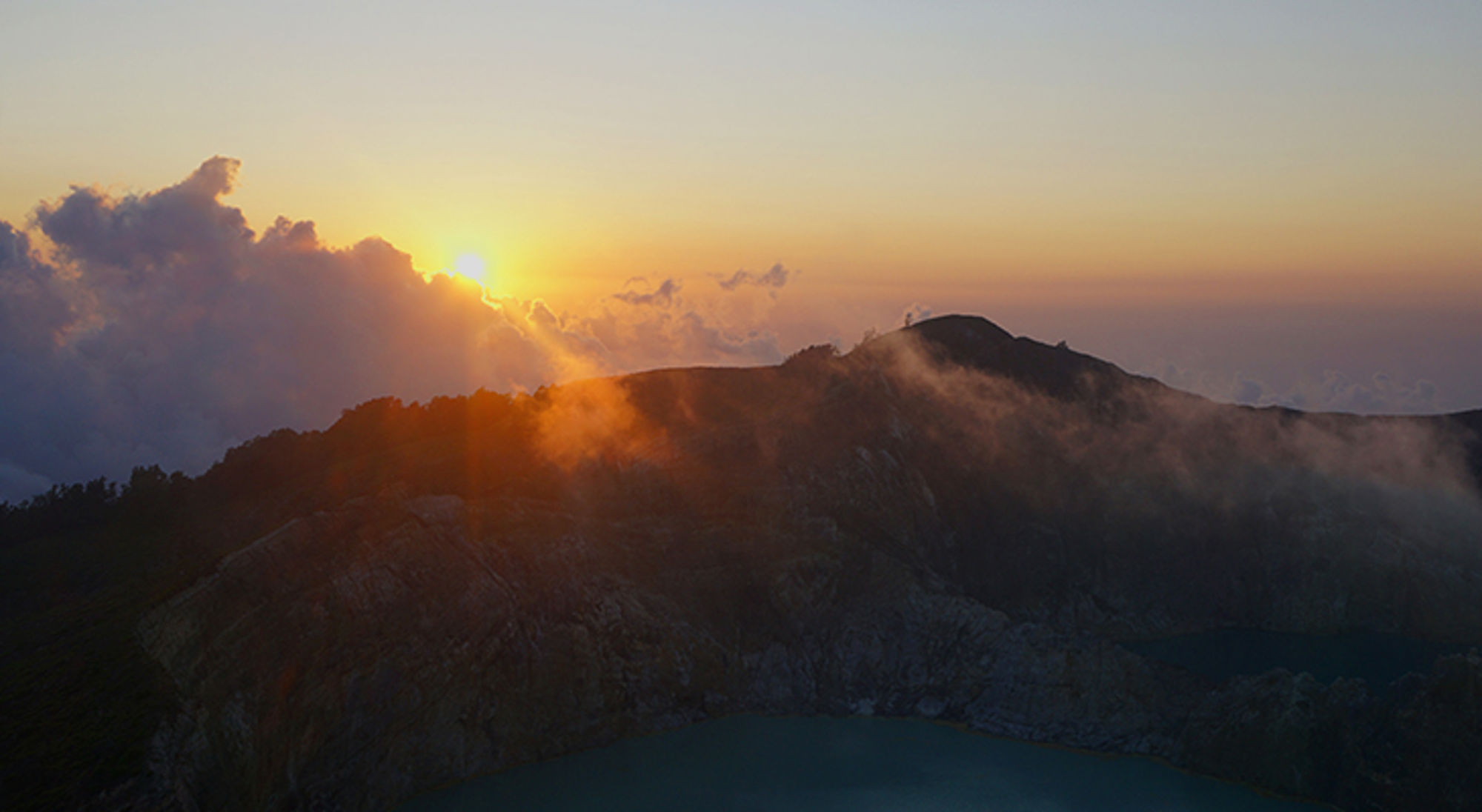 Zonsopkomst boven een vulkaankrater met mist en kratermeer in Indonesië.