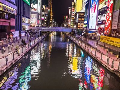 Avondzicht op het Dotonbori-kanaal in Osaka met neonreclames en reflecties in het water.