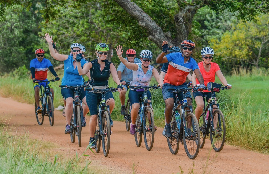 Groep fietsers tijdens een fietsvakantie in Sri Lanka op een onverharde weg door groen landschap.
