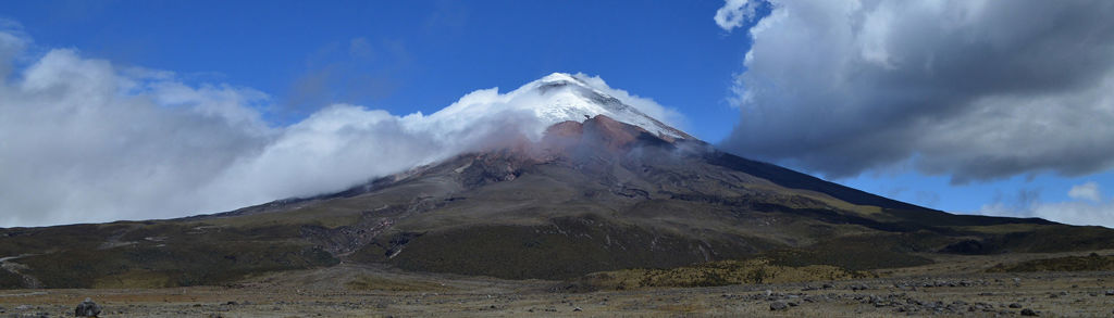 Besneeuwde vulkaan Cotopaxi in Ecuador met wolken en blauwe lucht.