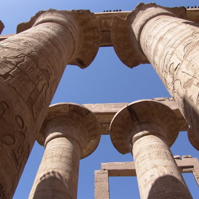 Zuilen met hiërogliefen bij een Egyptische tempel, gezien van onderaf tegen een blauwe lucht.