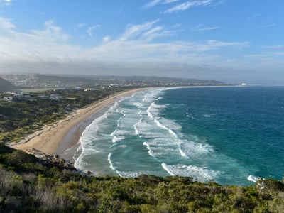 Panoramisch uitzicht op een lange zandstrandkust met golven langs Route Zuid-Afrika.