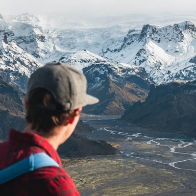 Groepsreis 22-35ers in IJsland met uitzicht op bergen en een waterval.