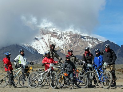 Mountainbikers bij een besneeuwde vulkaan in Ecuador tijdens de Route Ecuador, 21 dagen.