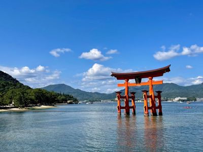 Rode torii-poort in zee bij Miyajima, Japan, met bergen op de achtergrond.