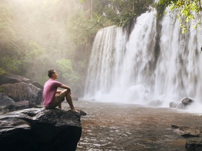 Reiziger bij een waterval in de jungle tijdens de route Thailand, Laos & Cambodja.