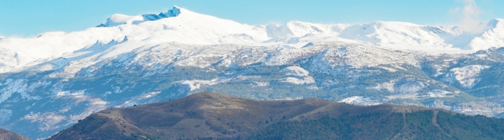 Besneeuwde bergtoppen van de Sierra Nevada in Spanje onder een heldere blauwe lucht.