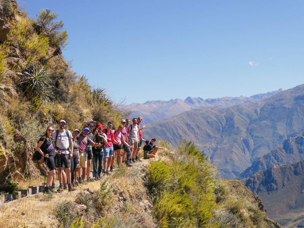 Groep 22-35ers wandelt langs bergpad in Peru met uitzicht op de Andes.