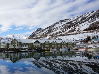 Seyðisfjörður in Noord-IJsland met haven, vissersboten en besneeuwde bergen.