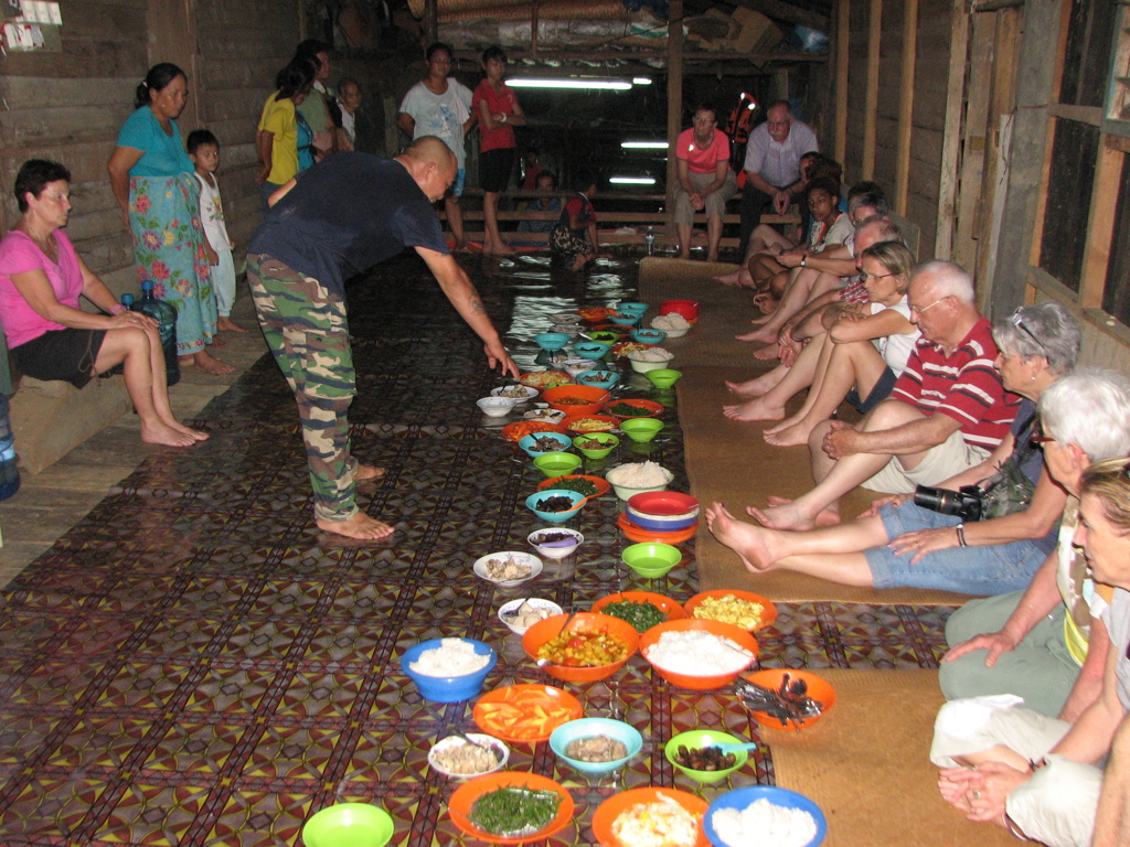 Gezamenlijke maaltijd in een longhouse in Sarawak, Maleisisch Borneo, met schalen eten op de vloer.