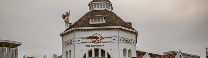 Hoofdpostkantoor Pos Indonesia in Medan, wit gebouw met rood dak aan een brede straat.