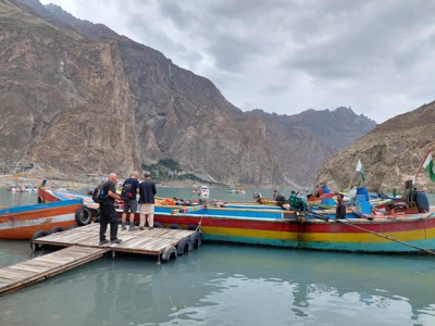 Kleurrijke boten aan een steiger op de Attabad Lake in Hunza, Pakistan, met ruige bergen op de achtergrond.
