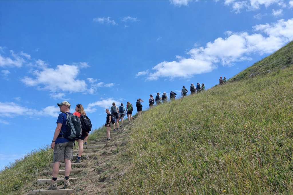 Wandelaars met rugzakken op een steil pad op São Miguel, Azoren, onder een blauwe lucht.