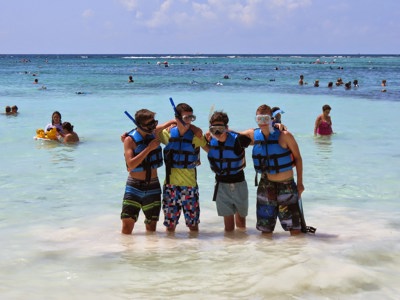 Snorkelaars met zwemvesten in ondiep turquoise zeewater aan een strand in Mexico.