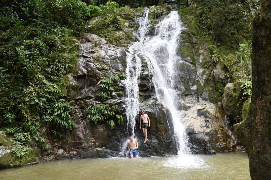 Waterval in het regenwoud in Colombia met twee reizigers bij een natuurlijke poel.