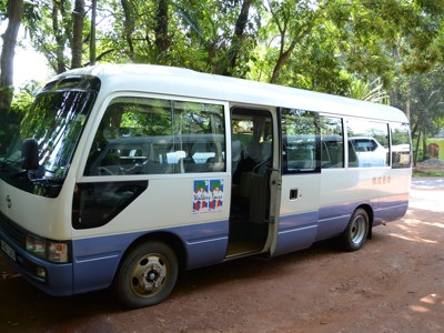 Witte minibus voor groepsreis op de Route Sri Lanka, geparkeerd in een groene omgeving.