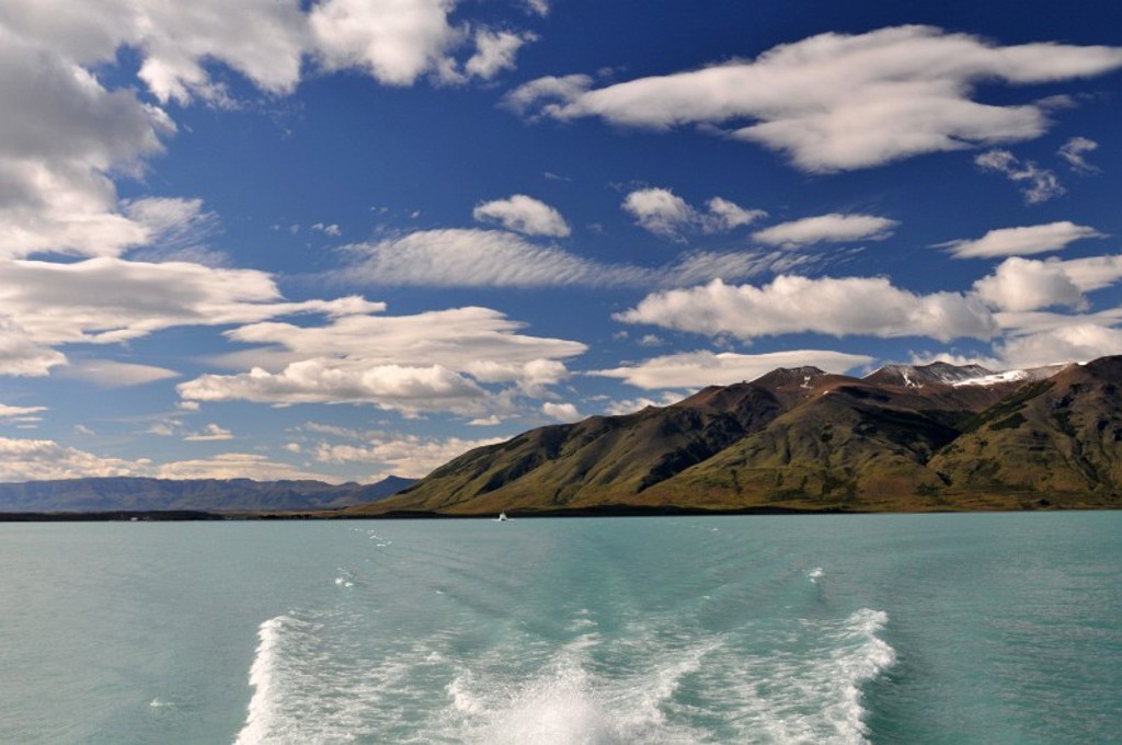 Uitzicht op een turquoise meer met bergen in Patagonië, gezien vanaf een boot met schuimend kielzog.