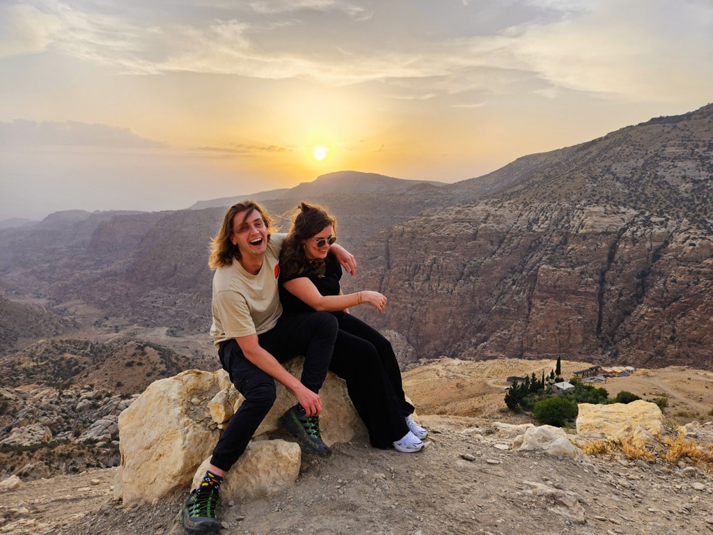 Jong stel op rots met uitzicht op berglandschap bij zonsondergang tijdens 22-35ers reis Jordanië.