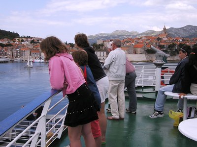 Gezin op het dek van een boot met uitzicht op de haven en oude stad van Korčula, Kroatië.