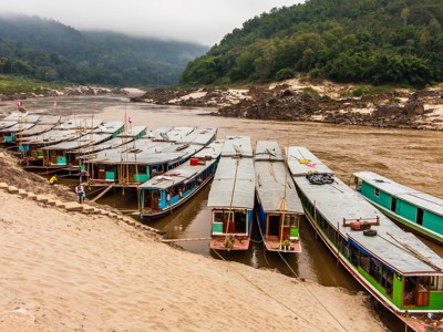 Aangemeerde boten op de Mekong bij groene heuvels tijdens de Route Laos & Cambodja.