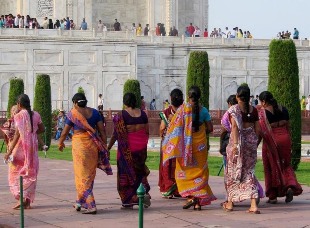 Bezoekers in kleurrijke sari’s lopen langs de Taj Mahal in Agra tijdens een groepsrondreis Noord-India.